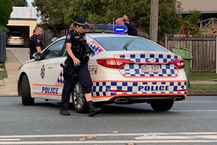 A policewoman has her pants rolled up on one leg and there is blood on it