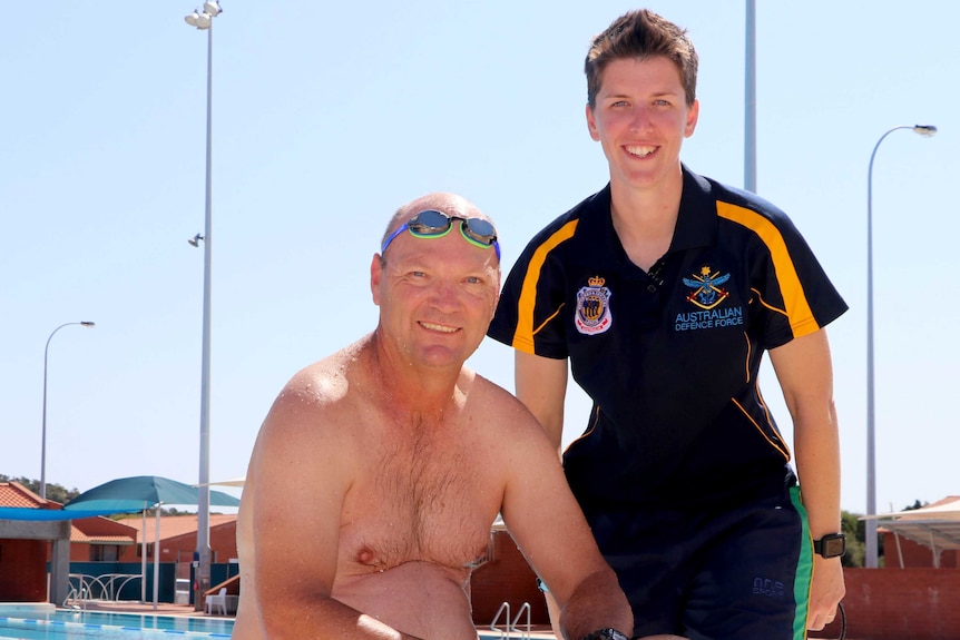 Petty Officer Ian McCracken and Lieutenant Amy Beal of the Australian Defence Force on the edge of a pool.