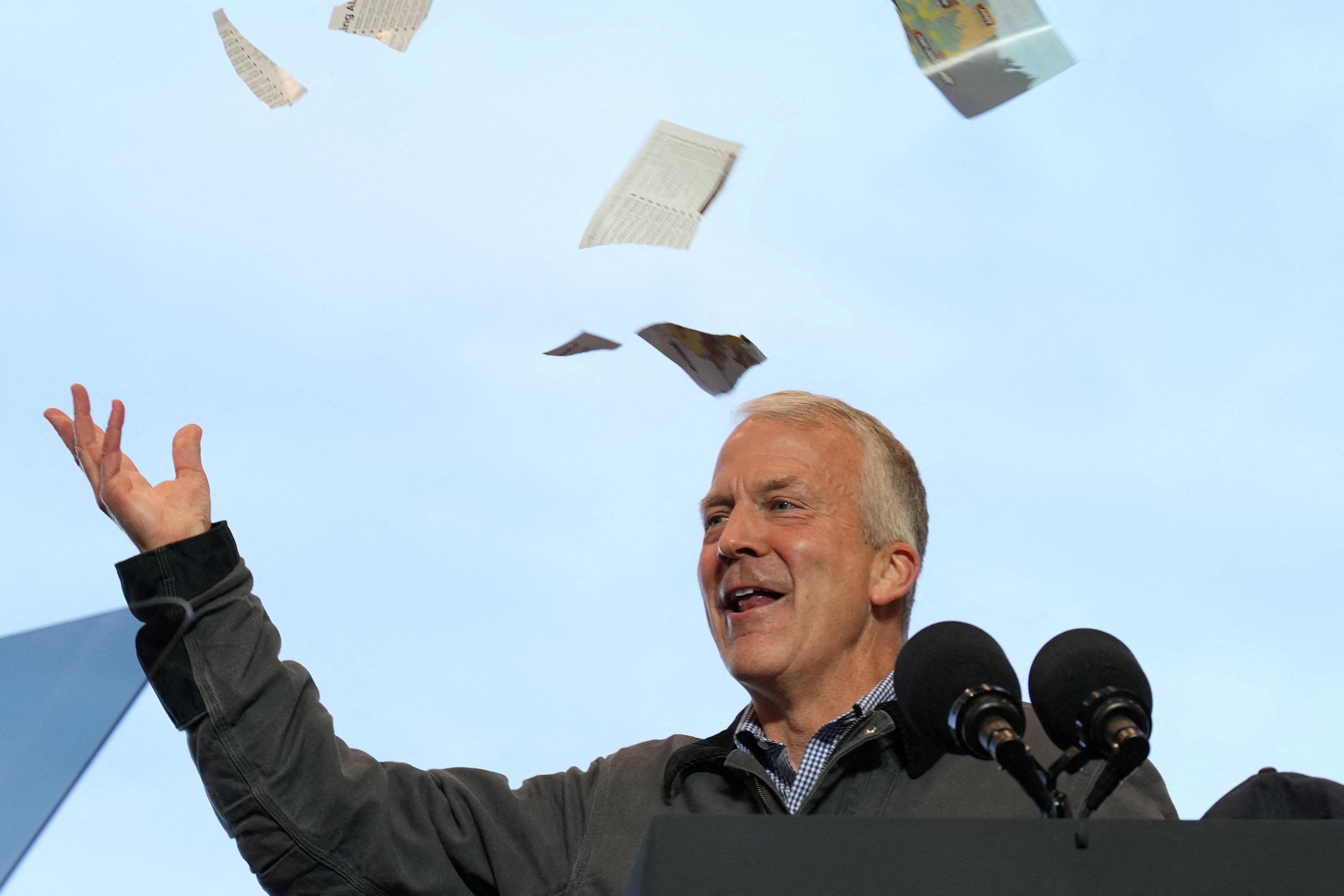 US Senator Dan Sullivan tosses torn paper into the air as he speaks at a campaign rally