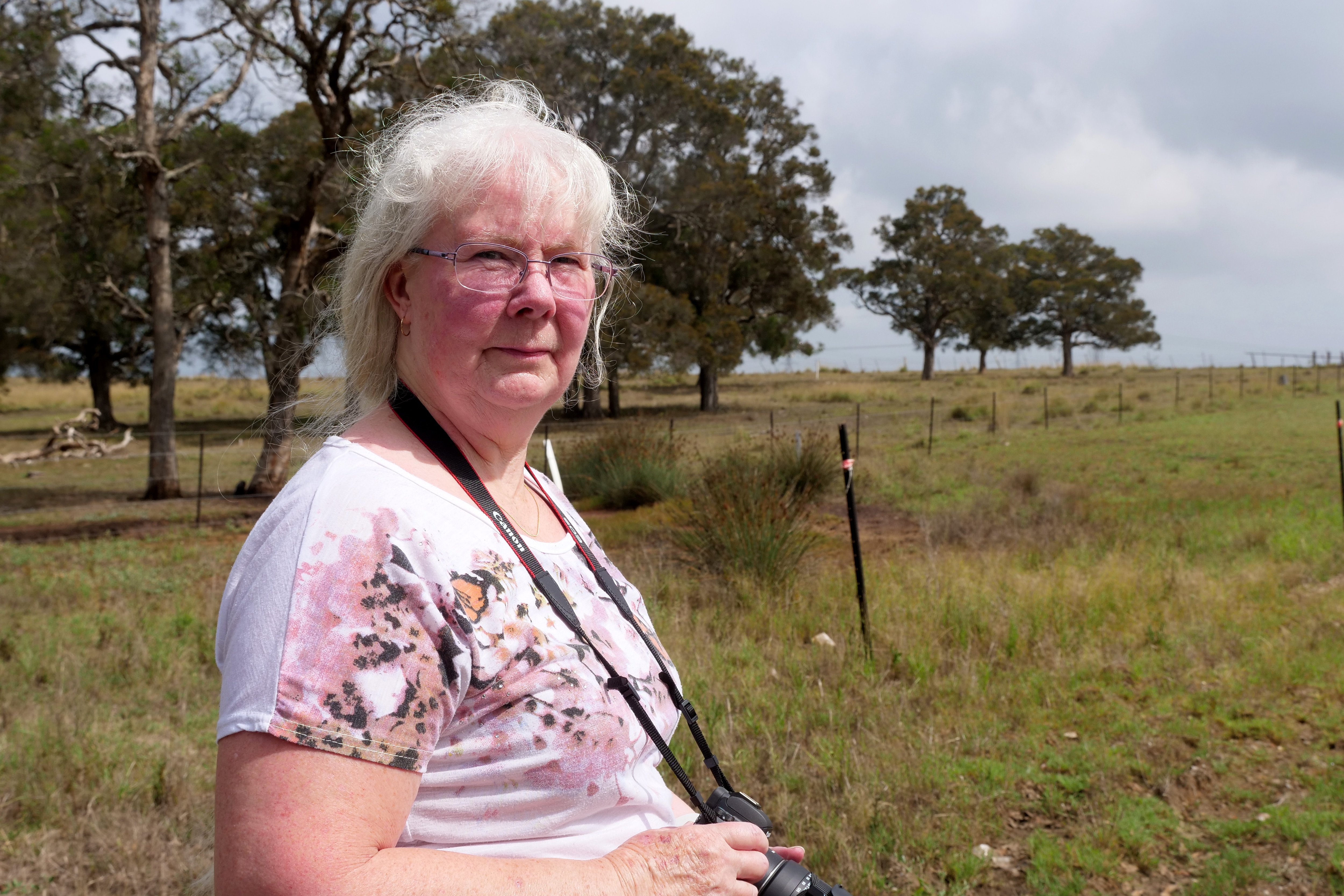 uma mulher com uma câmera pendurada no pescoço olha para frente