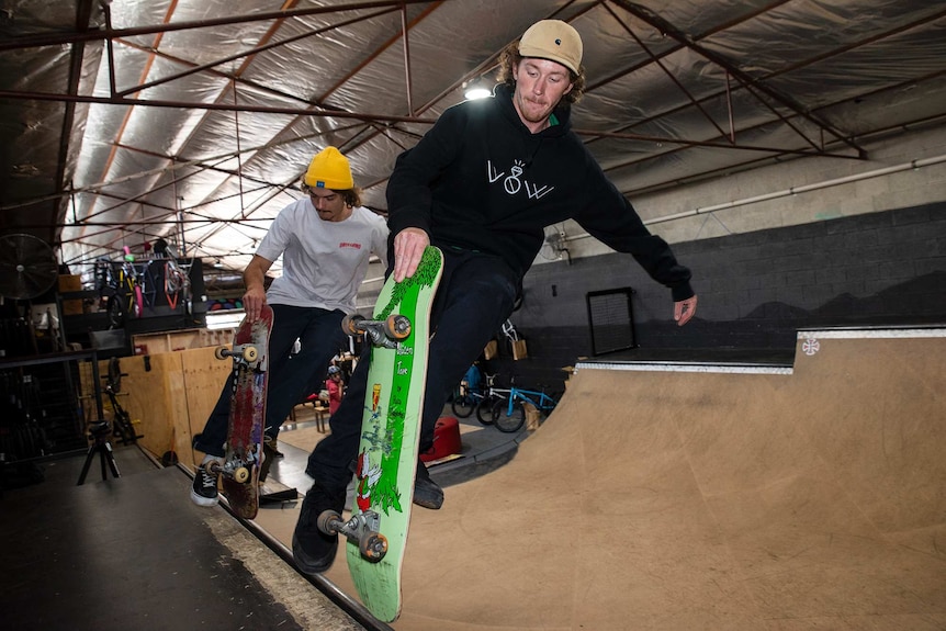 Two skateboarders hit the lip of a skate ramp at once.