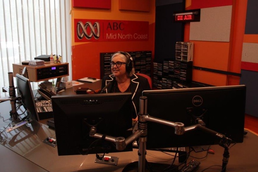 Wyllie with headphones on behind mic in ABC radio studio.