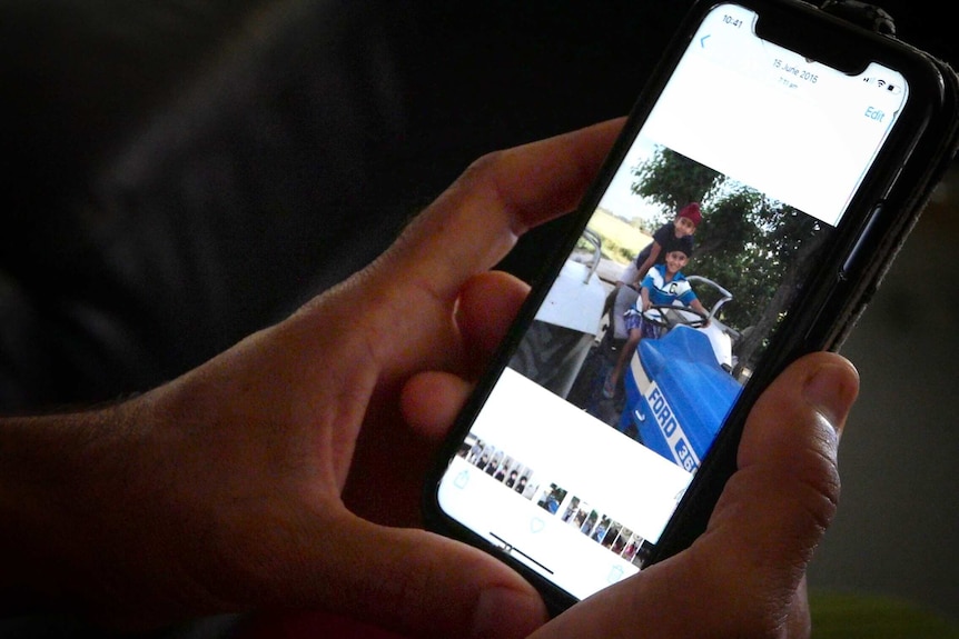 A closeup photo of two children on a phone being held by Hardeep Mander.