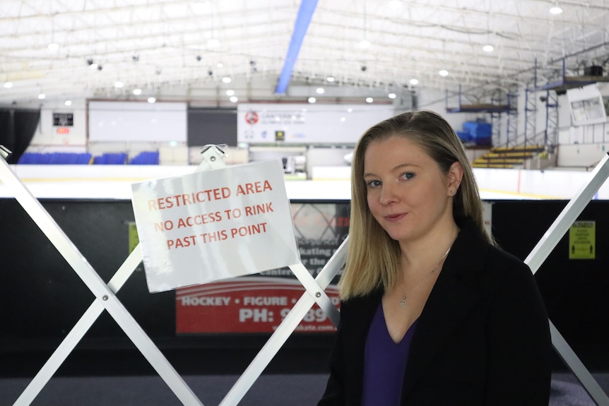 a woman sitting down next to a sign that reads restricted area