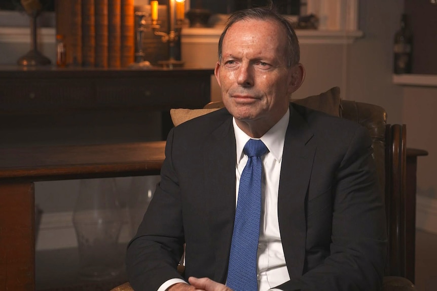 A man sitting in a chair wearing a suit and tie.