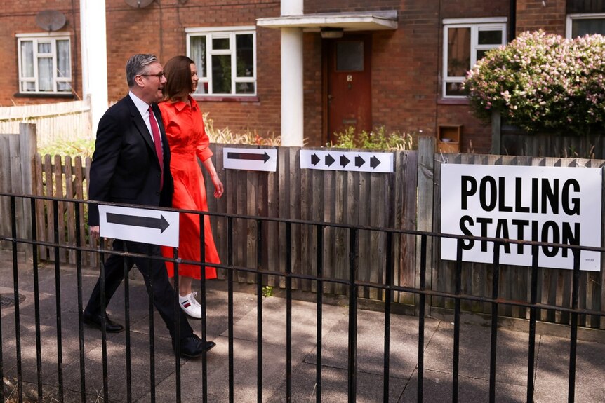 A man and a woman walk past a sign indicating 