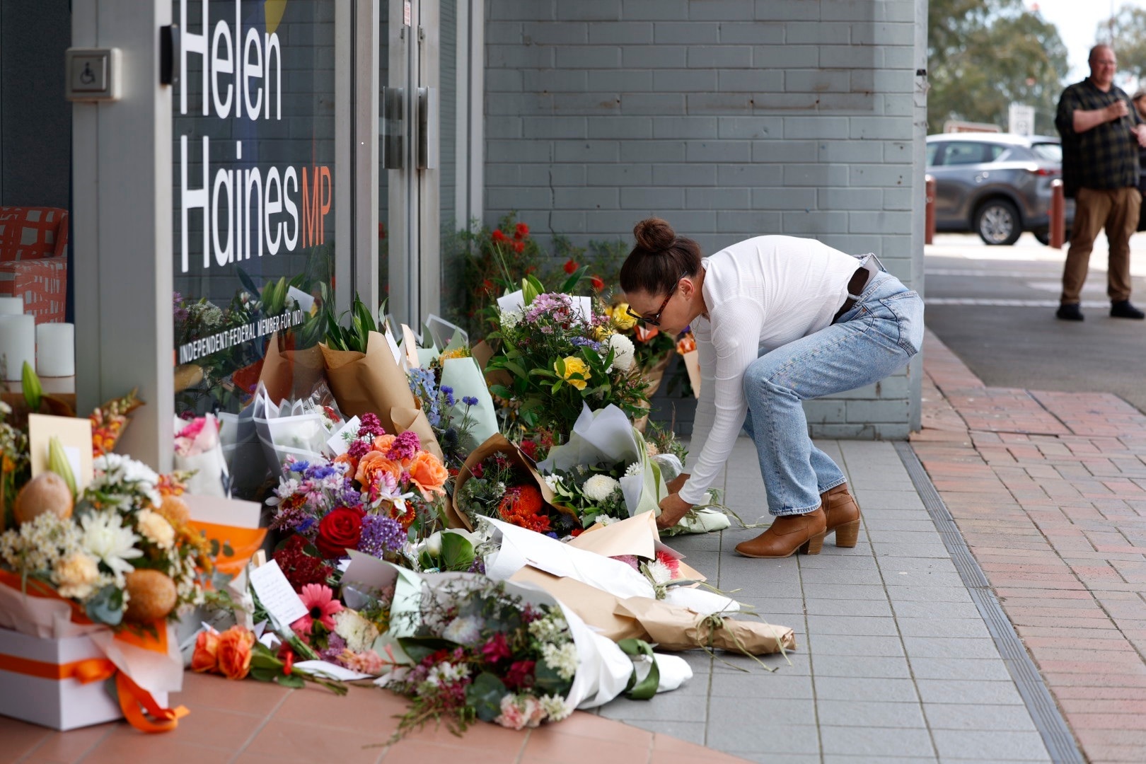 woman in jeans putting flowers at office door