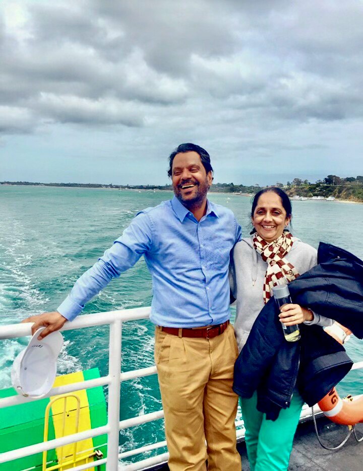 Jaswinder Singh and Sukhdeep Kaur smile together arm in arm on a boat at sea.