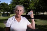 A cross woman holds up a debit card