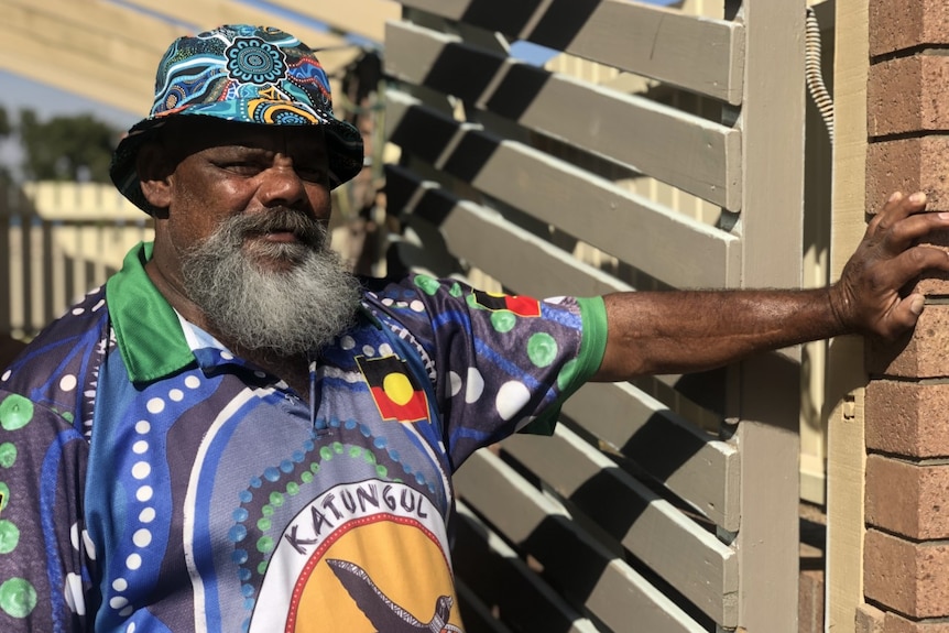An older Indigenous man wearing a colourful outfit with traditional patterns.