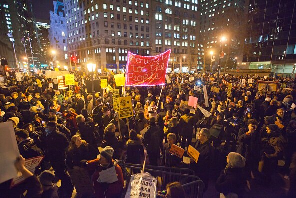 Protestors fill a public square in New York city holding placards