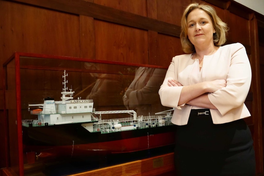 Teresa Lloyd from Maritime Industry Australia stands in front of a model ship with arms folded.