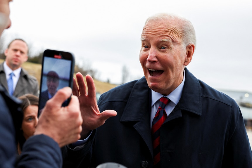 Joe Biden smiles and waves to a video a reporter takes of him