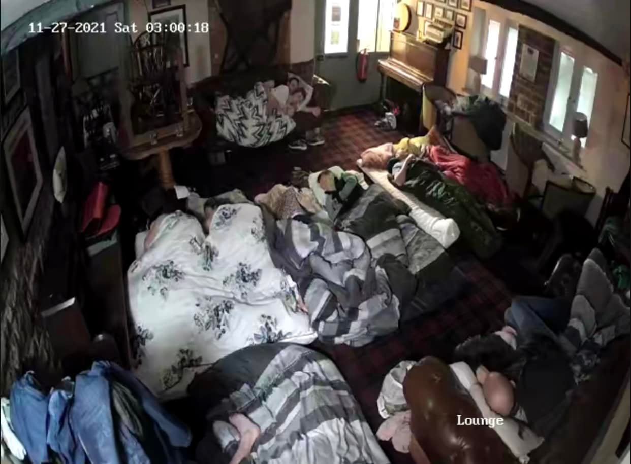 People sleeping in blankets on the floor of a pub.
