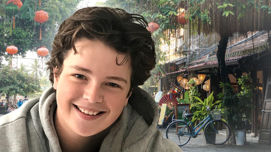 A boy's smiling face is superimposed over a background of a Vietnamese street