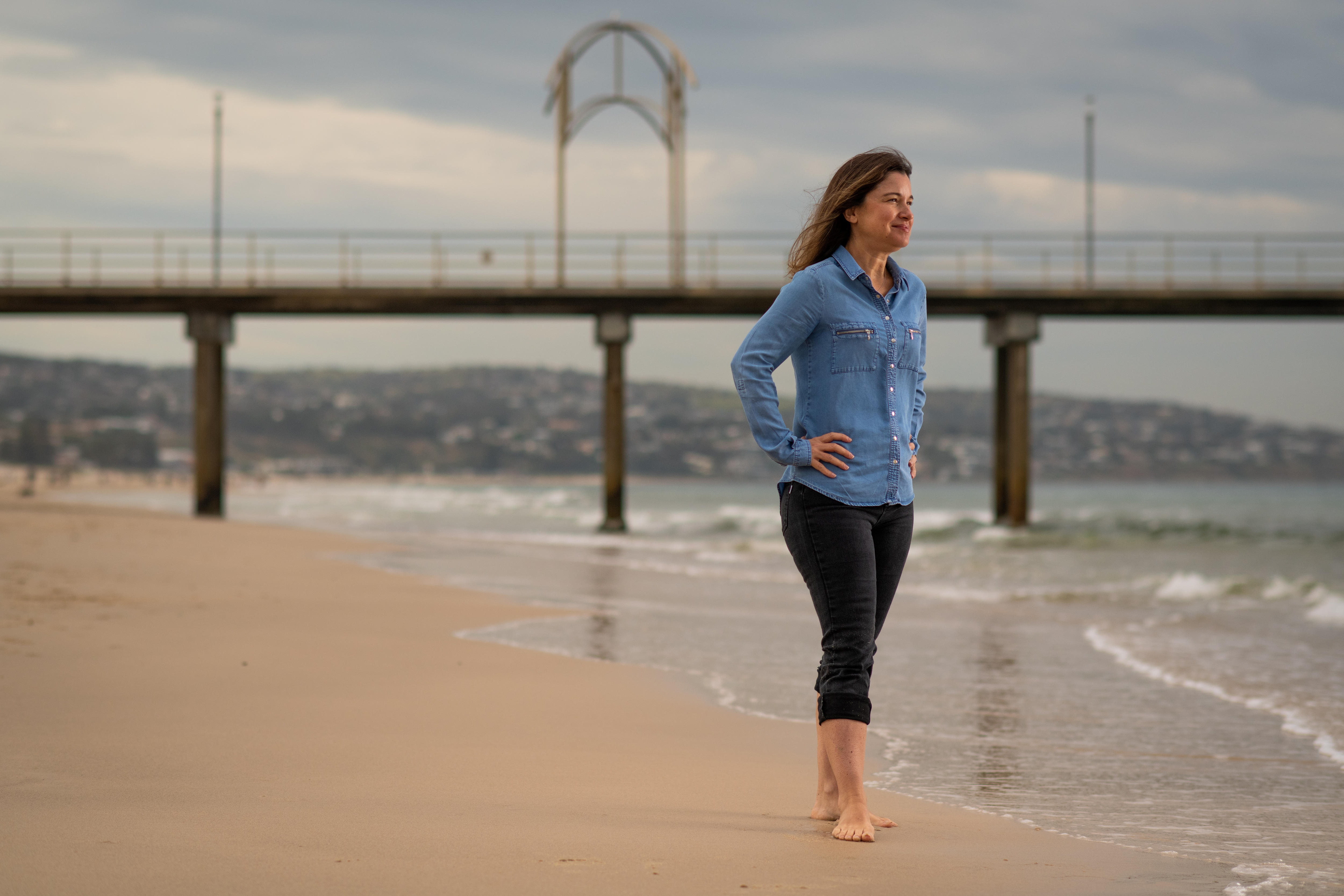A woman stands near the shoreline at Brighton in coastal Adelaide.