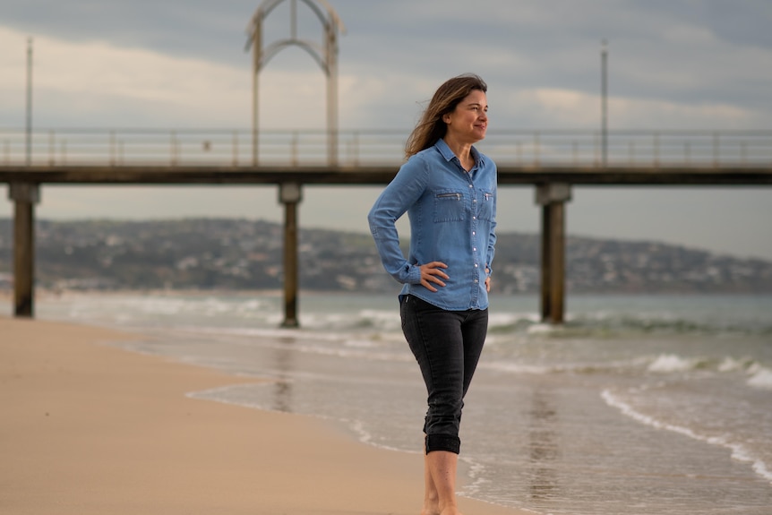 A woman stands near the shoreline at Brighton in coastal Adelaide.