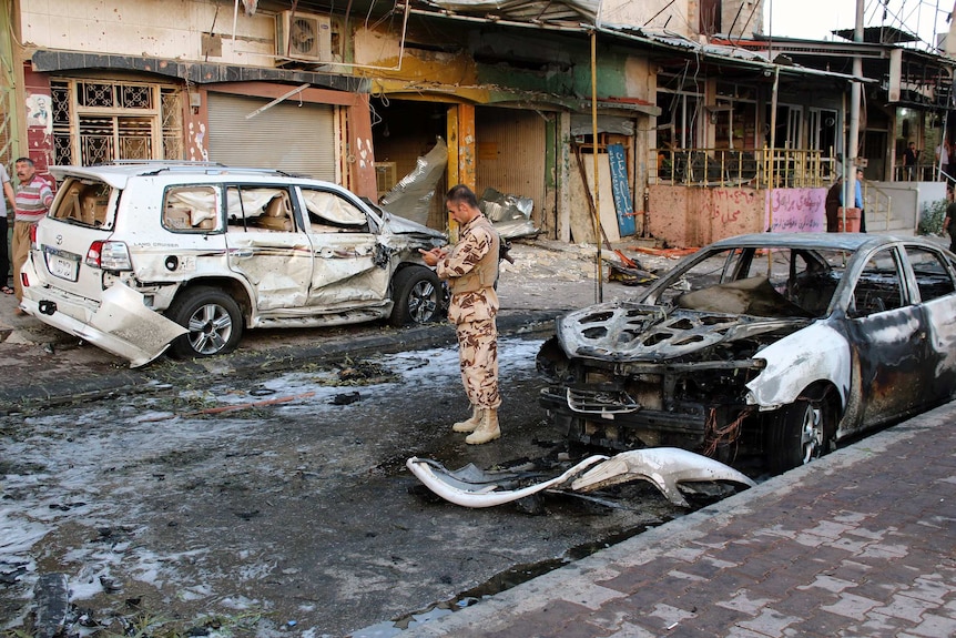 A member of the Kurdish security forces inspects the site of a suicide bombing attack in Kirkuk.