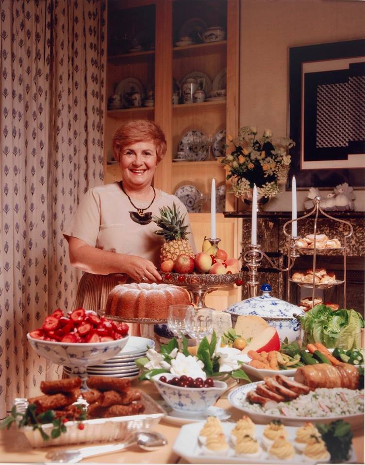 Woman stands before a table laden with food