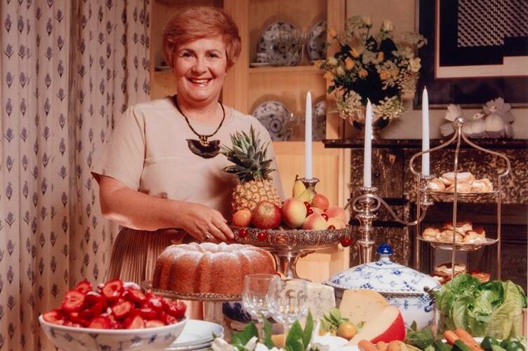 Woman stands before a table laden with food