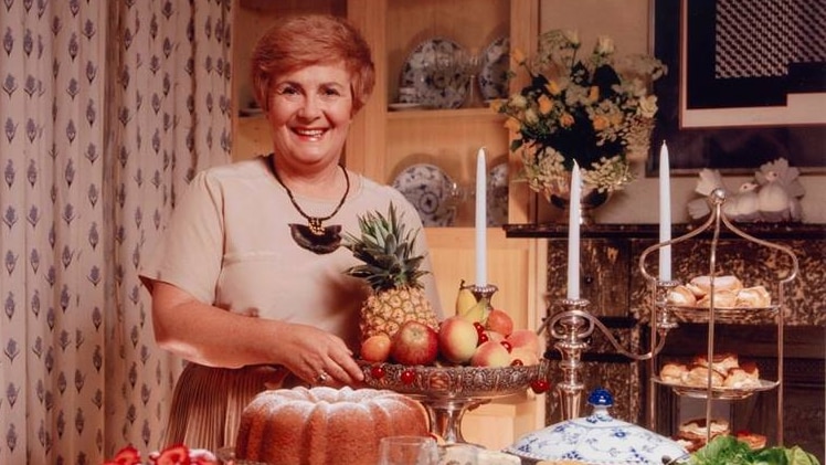 Woman stands before a table laden with food