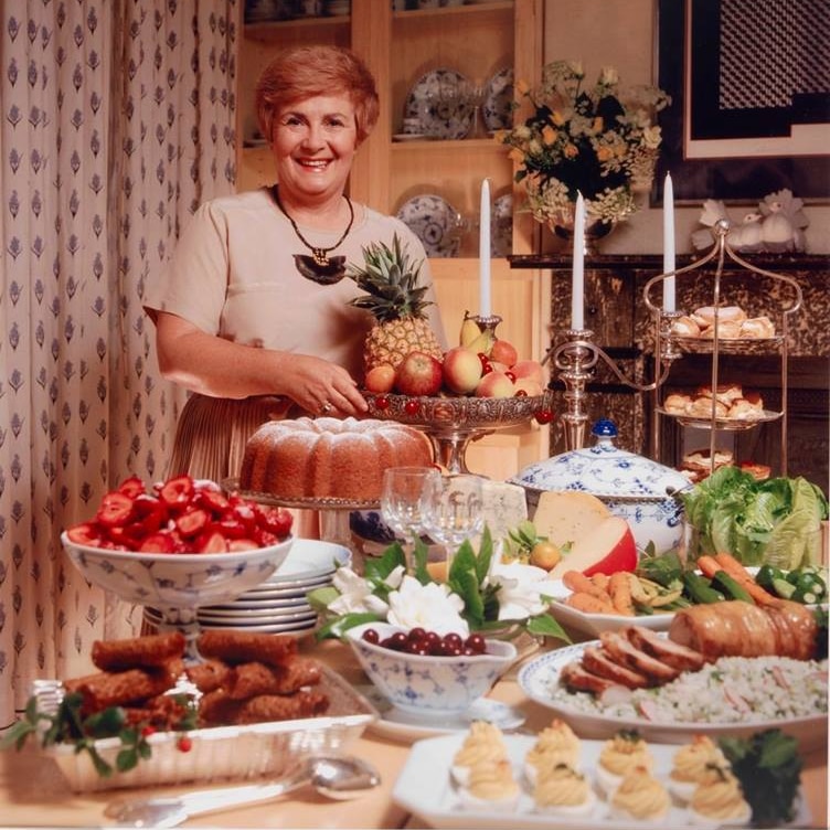 Woman stands before a table laden with food