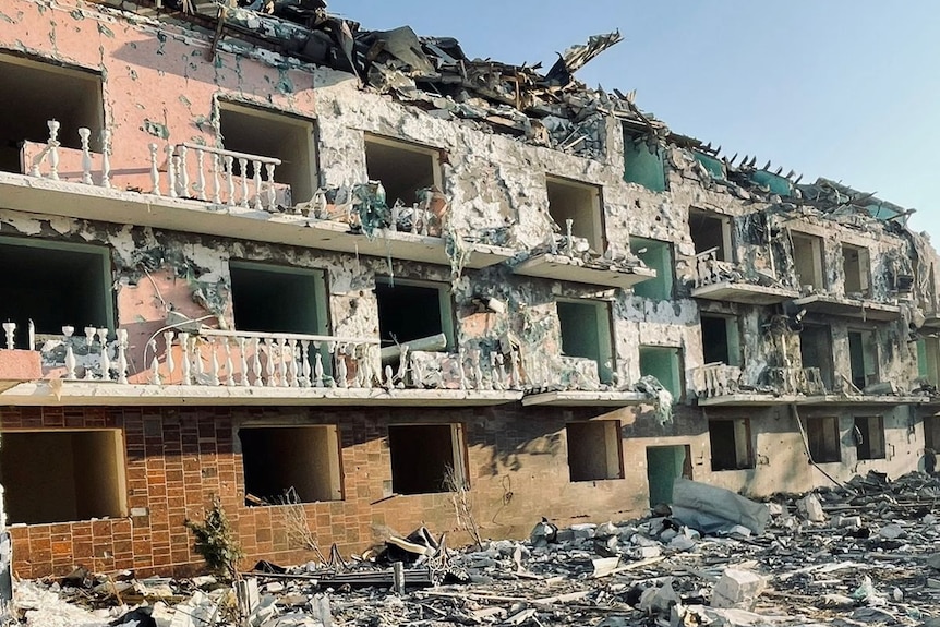a building hit by a Russian missile strike is shown destroyed with debris on the ground below