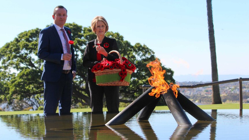 Premier standing in front of flame monument.