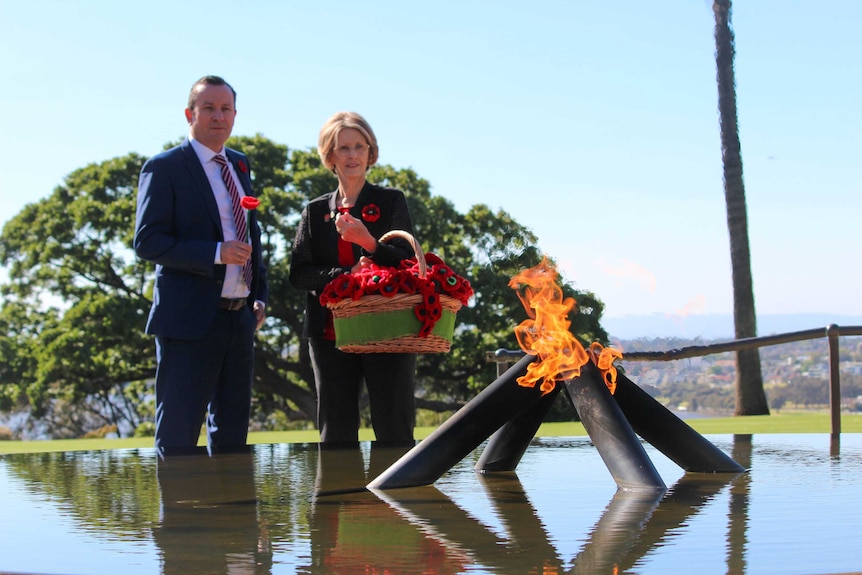 Premier standing in front of flame monument.