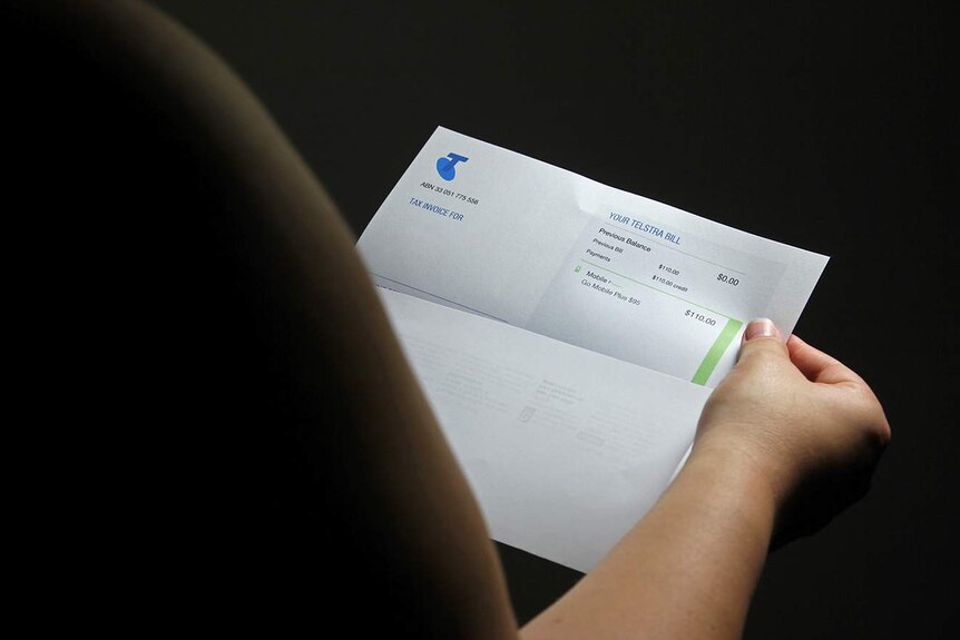 A photo of a Telstra phone bill being opened by a customer.