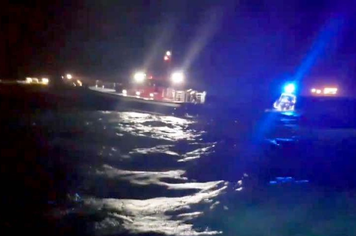 Rescue boats in the dark with lights shining off the water.