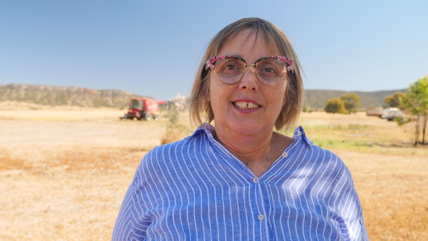 Sally West smiles at the camera with a rural landscape behind
