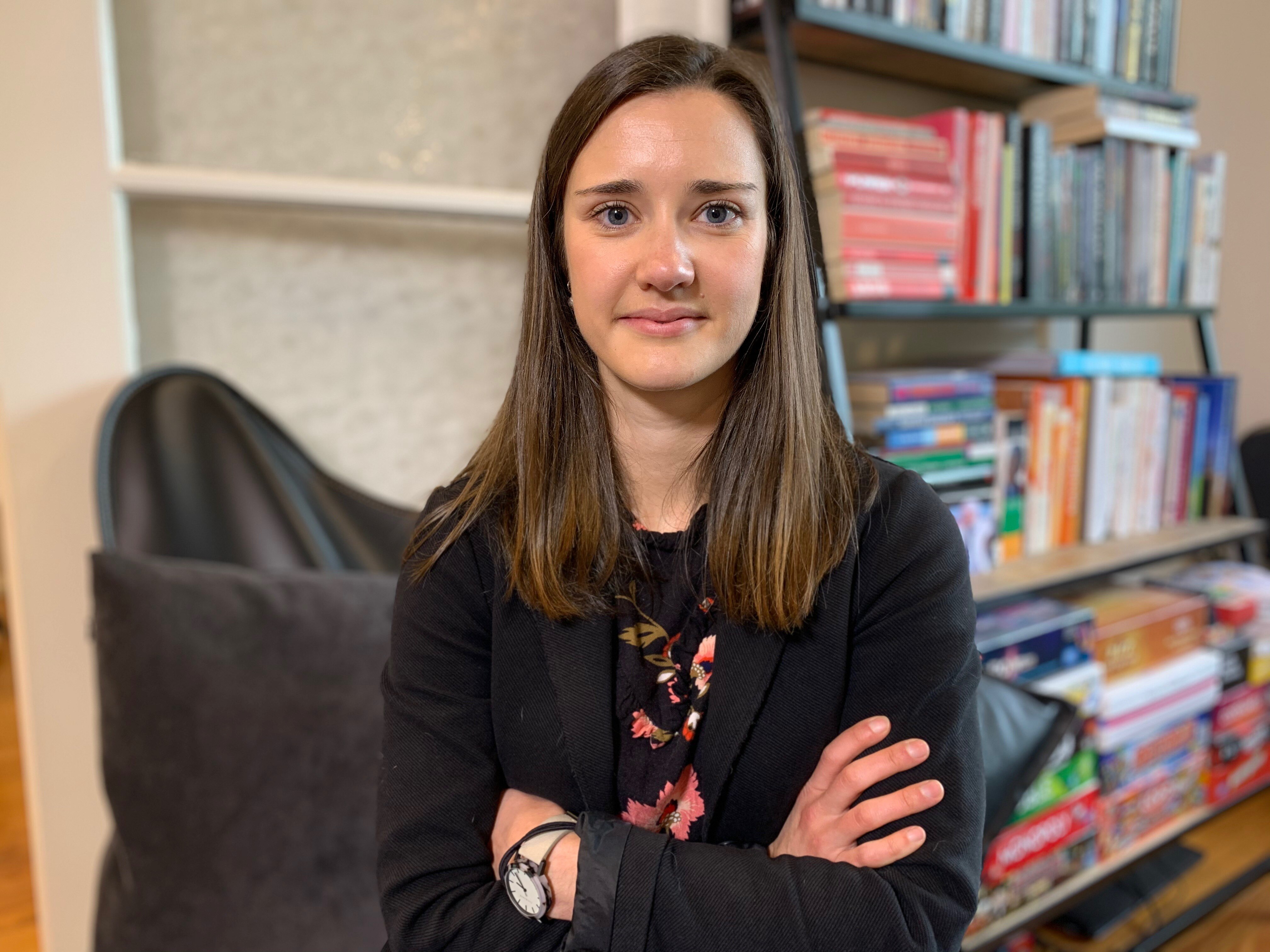 Young woman with brown hair wearing black jacket over black and floral top