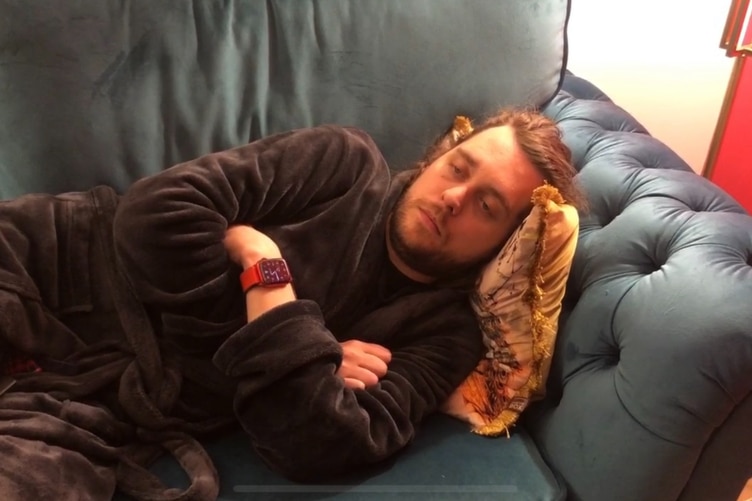 A man lays exhausted on a loungeroom sofa. 