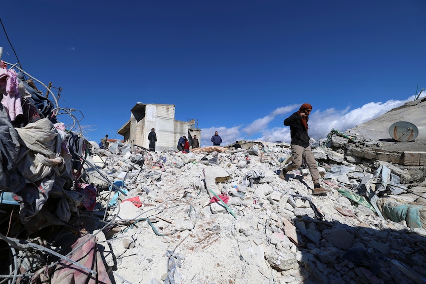 People search through the rubble of collapsed buildings.