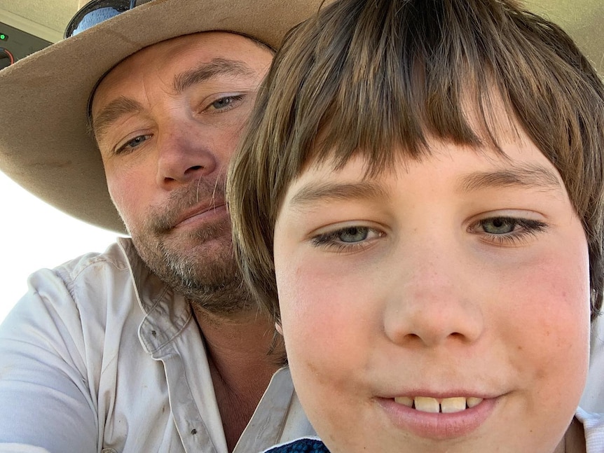 A farmer wearing a hat and his young son in a selfie-style shot.