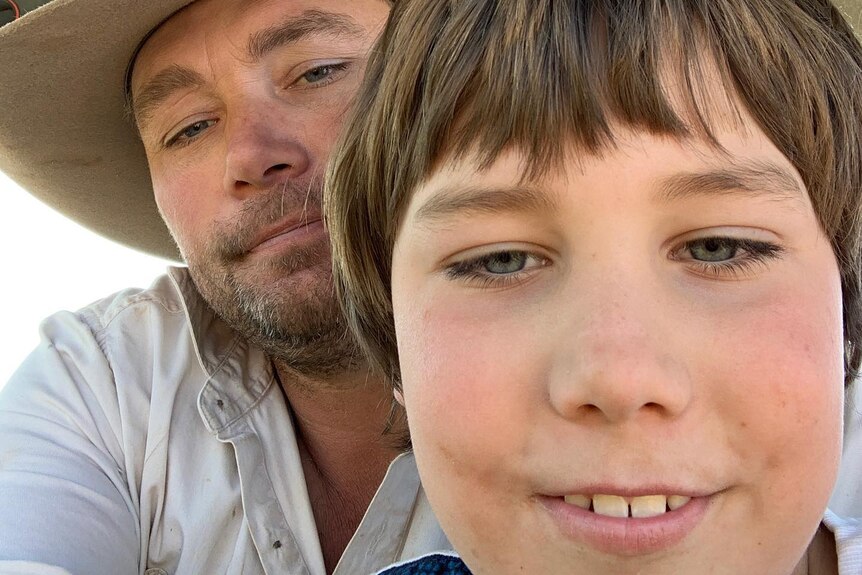 A farmer wearing a hat and his young son in a selfie-style shot.