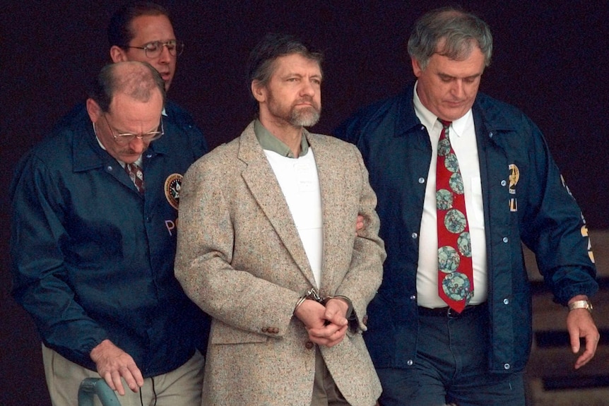 A man in suit held by police officials. 