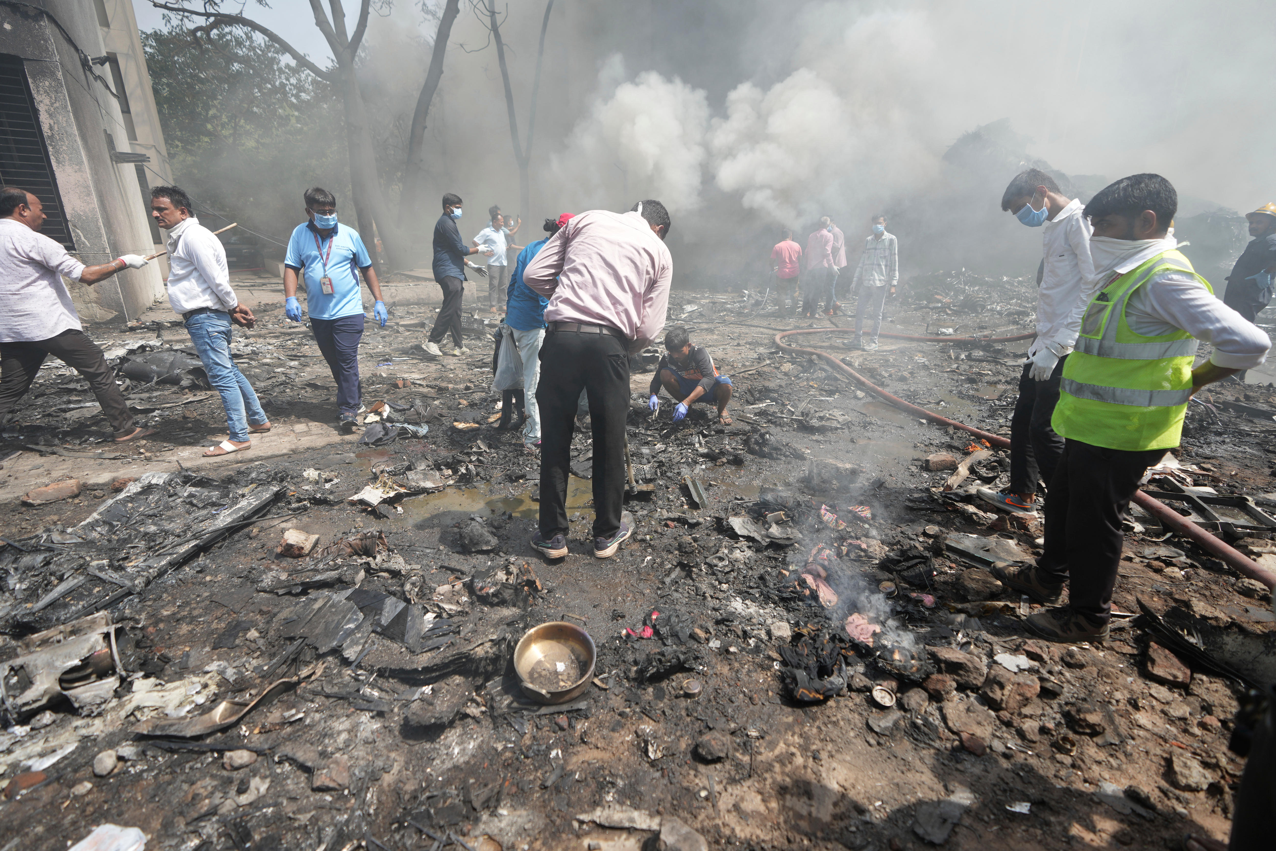 Male rescuers and bystanders searching through charred and smoking debris and wreckage on the ground