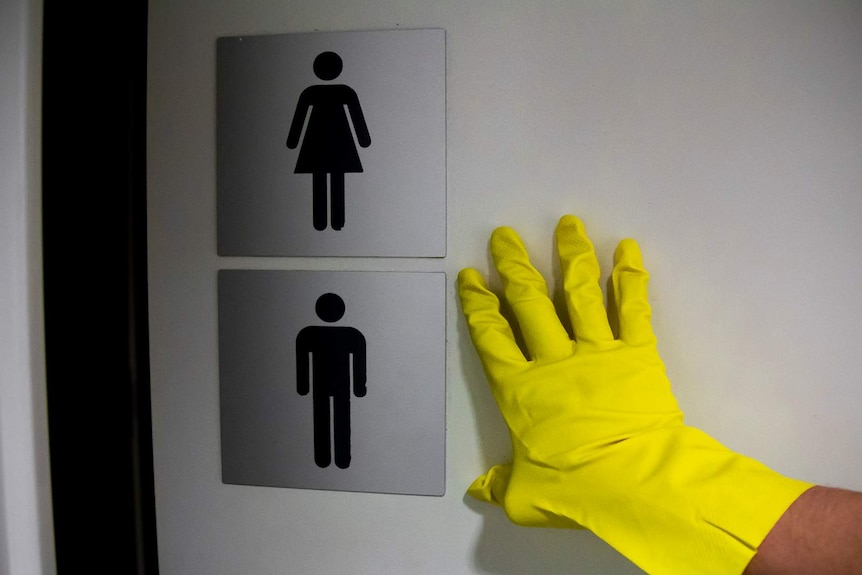 A gloved hand is pushing open a toilet door.