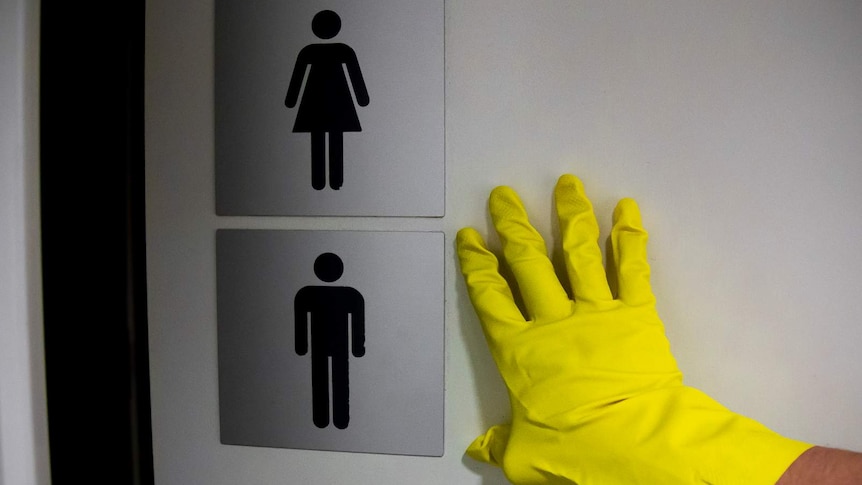 A gloved hand is pushing open a toilet door.