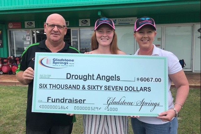 Volunteers hold up a giant cheque awarding $6067 to Drought Angels.