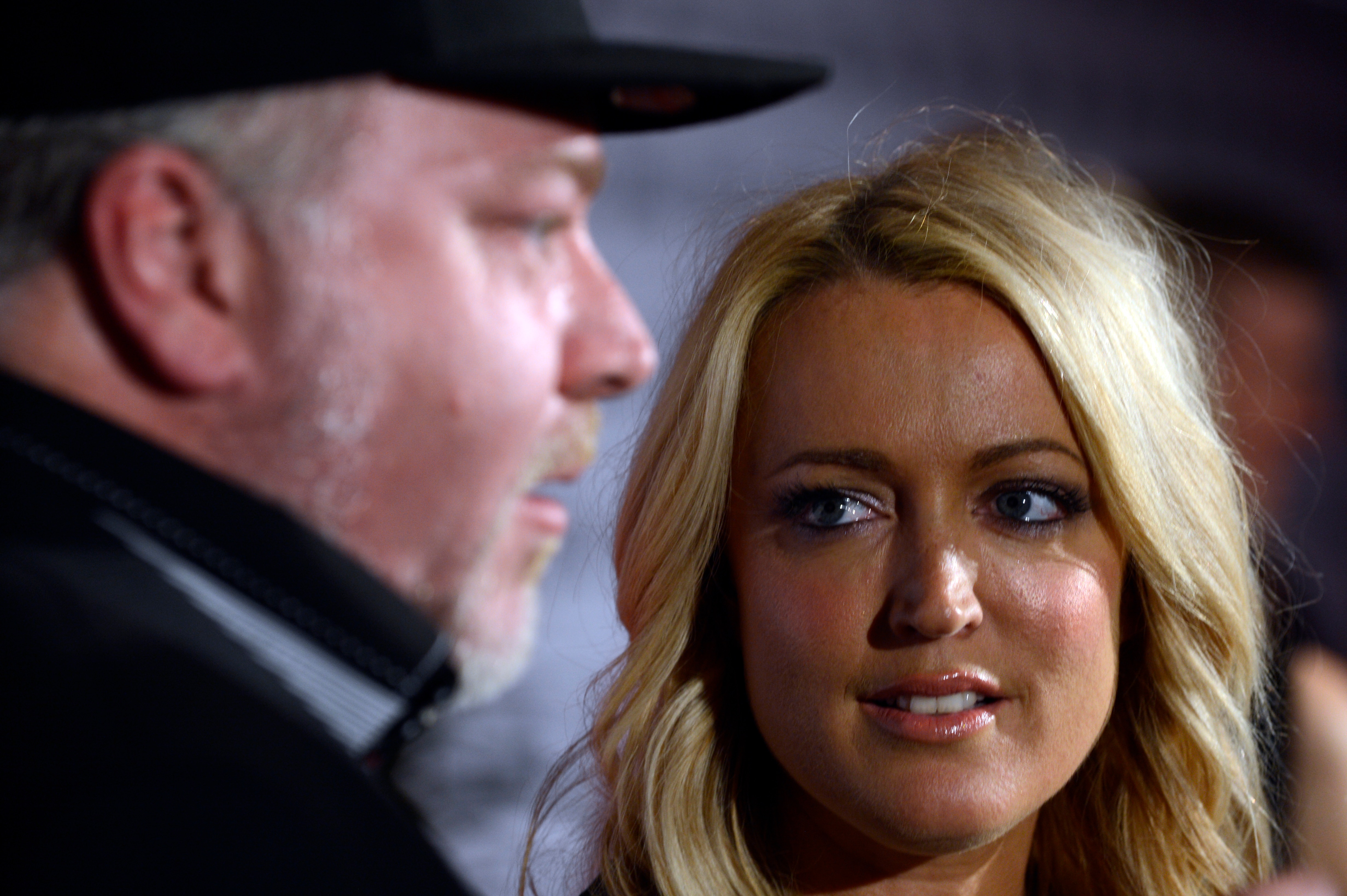 A bearded man and a blond woman look at each other