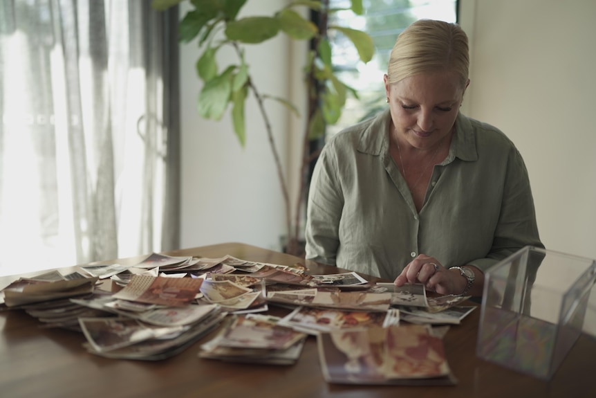 Sally Leydon looking at old family photographs at a table.