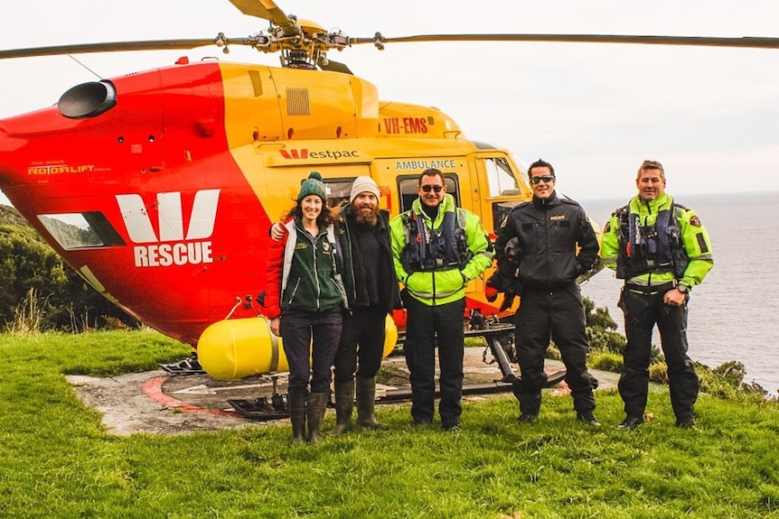 Picture of a group of people standing in front of a helicopter