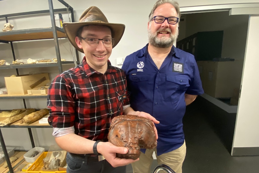 Two men holdinging a 3D replica of a trilobite's tail