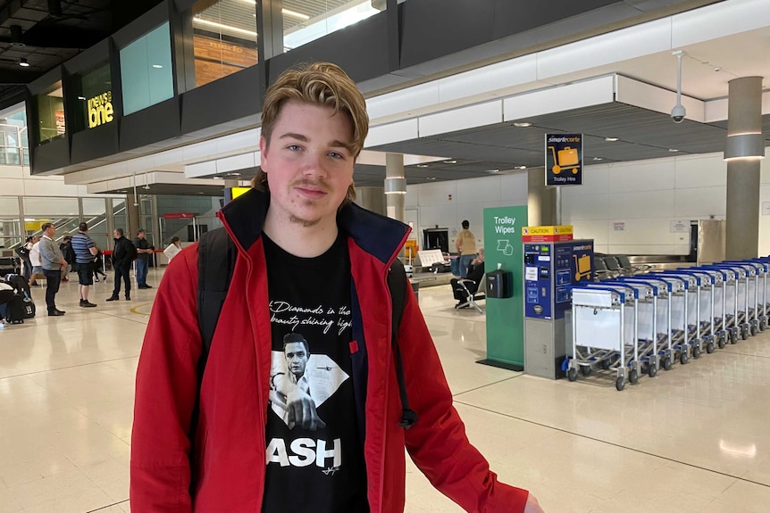 A young man wearing a jacket and backpack standing in Brisbane airport