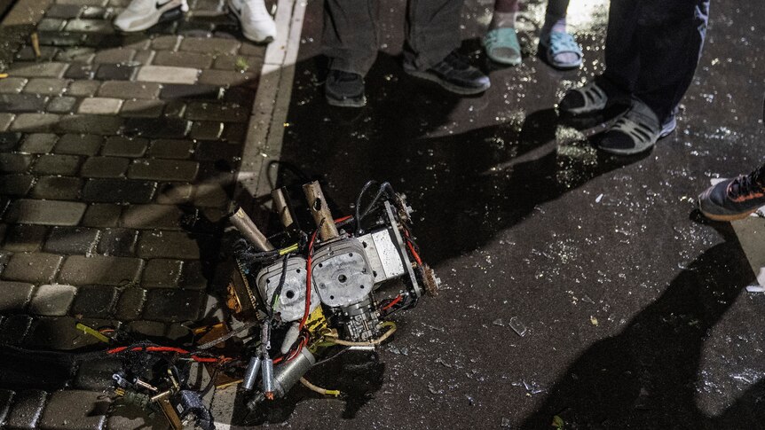 Wreckage of a drone sits on a street in Kyiv, as residents gather around it
