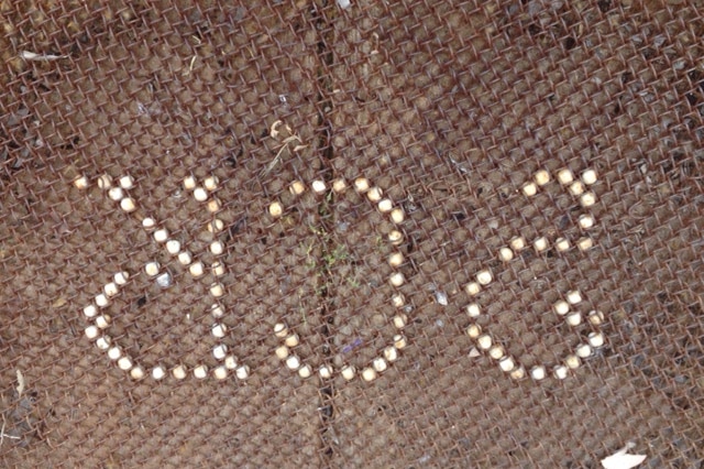 White marbles in a mesh doormat spelling out 2CR