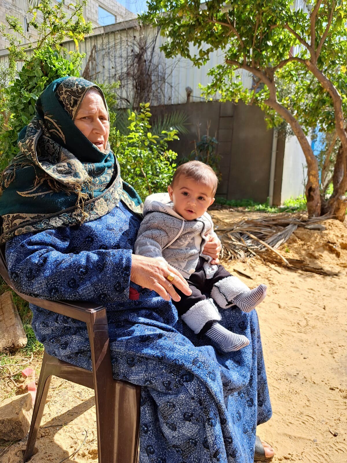 A woman sitting on a chair holding a young baby on her lap.
